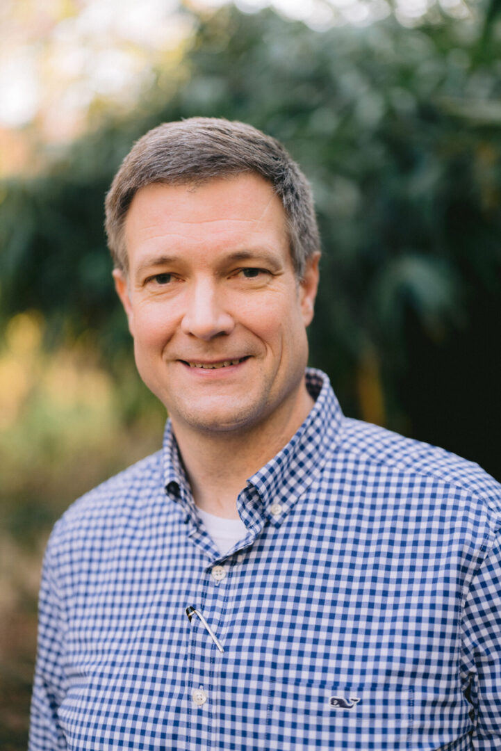 A man in a blue and white shirt smiling for the camera.