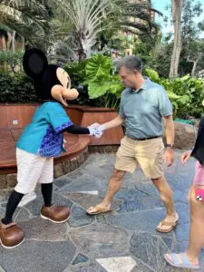 A man is shaking hands with mickey mouse.