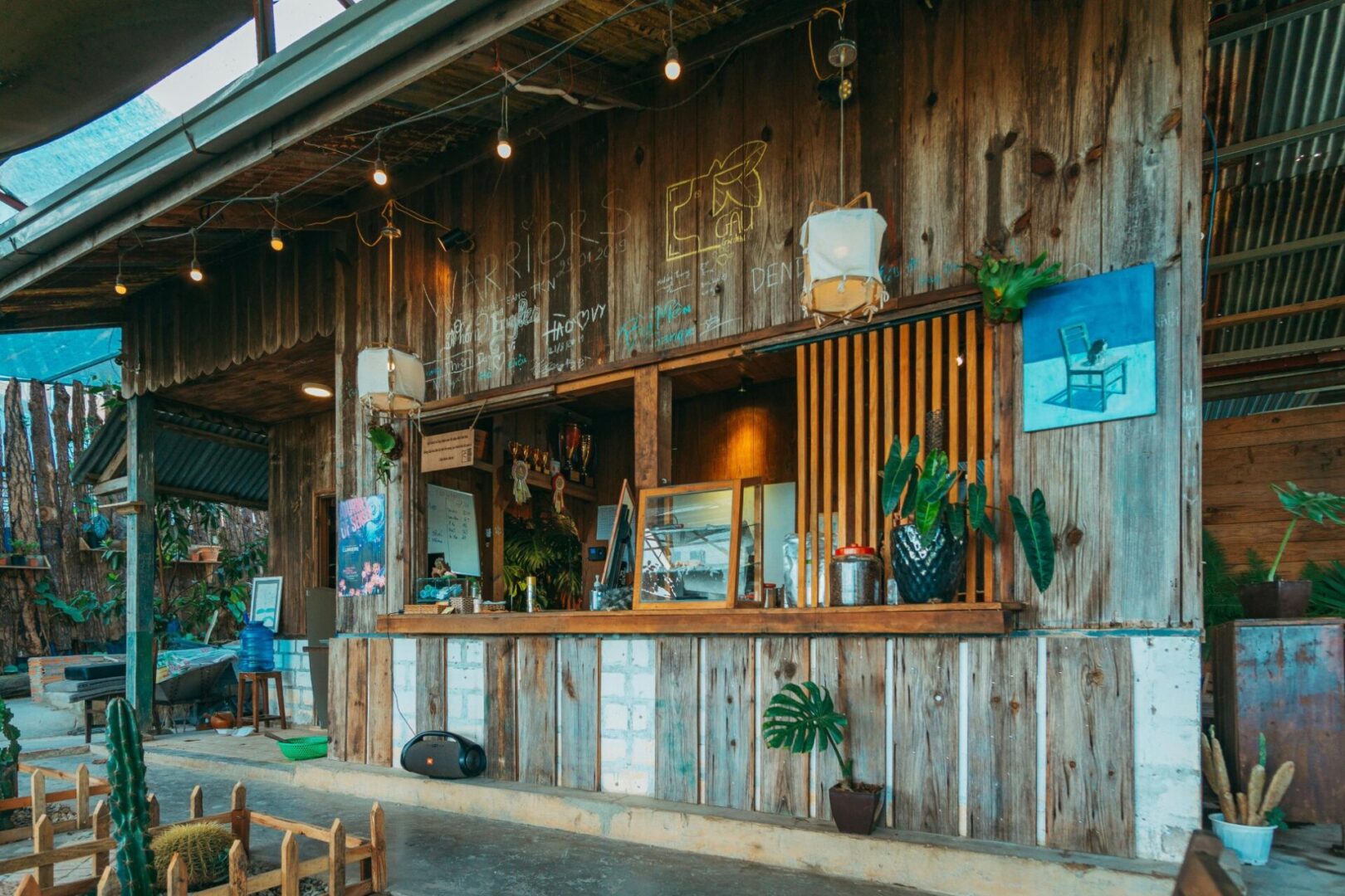 A wooden wall with plants and tables in front of it.