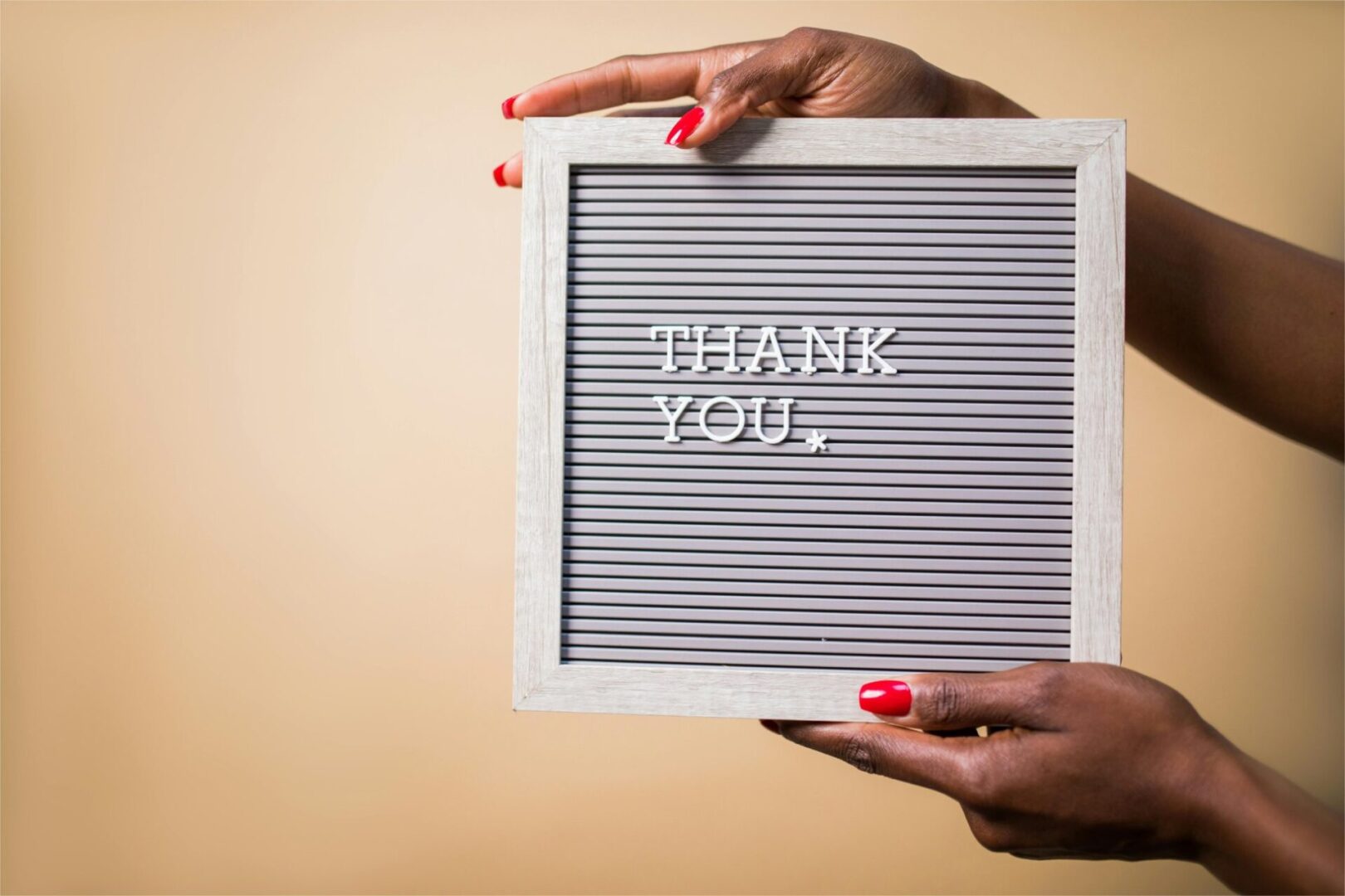 A person holding a letter board that says " thank you ".