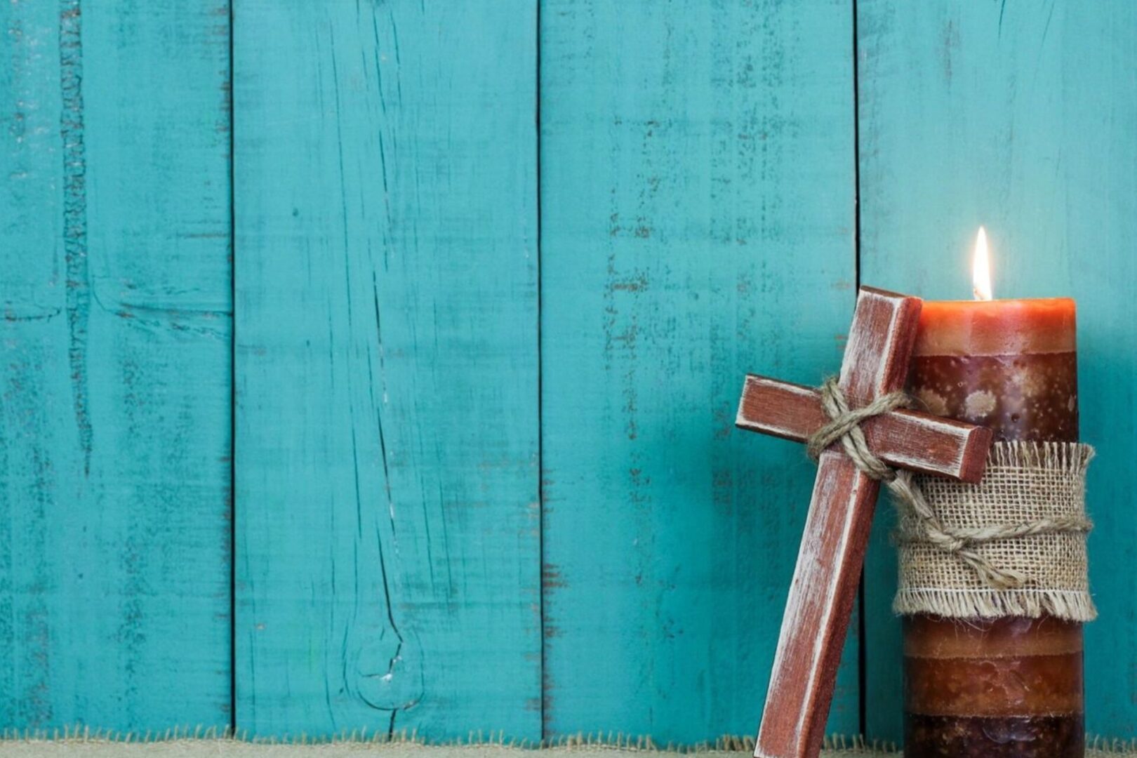 A wooden cross sitting on top of a blue wall.